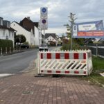 abgesperrte Baustelle; die Absperrung blockiert fast den gesamten Bürgersteig. Weiterkommen mit Kinderwagen, Rollstuhl oder Rollator ist nur über die Straße möglich