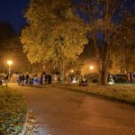 Im Park: eine Gruppe von Menschen hat sich versammelt. Ich stehe abseits, sehe die Gruppe, aber bin zu weit entfernt, um mit einer Person interagieren zu können.