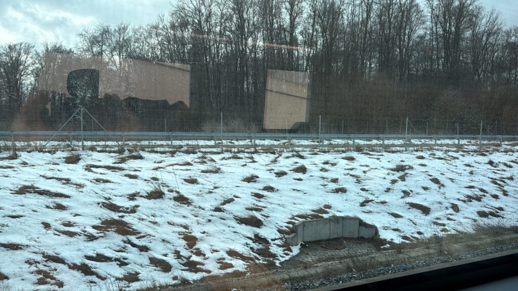 Blick aus dem Fenster bei einem Stopp zwischen Ulm und Stuttgart. Es liegt eine leichte Schneedecke und es ist ein leichter Schneefall zu sehen.